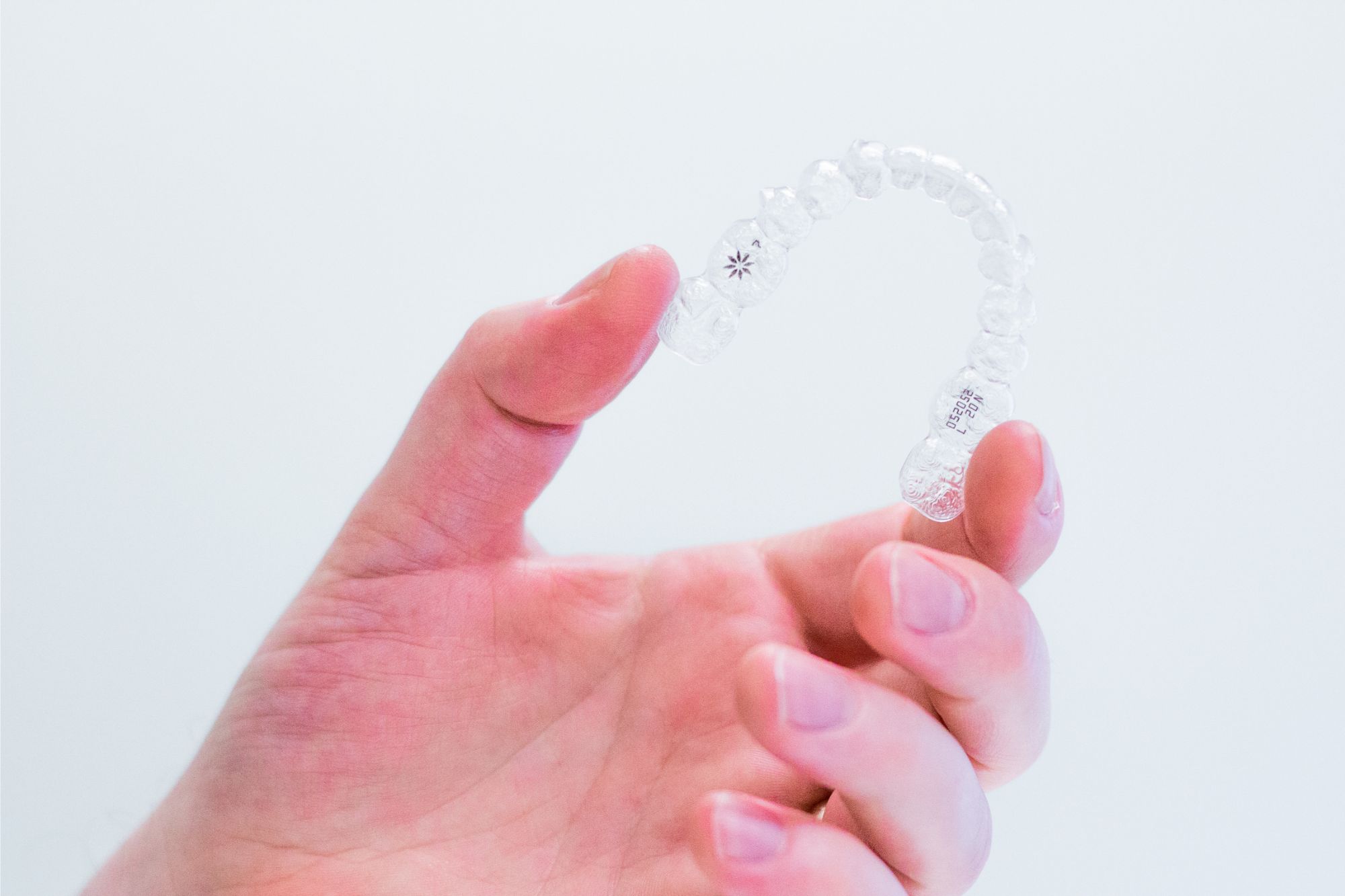 Hand holding clear Invisalign aligners provided by a Birmingham, MI orthodontist